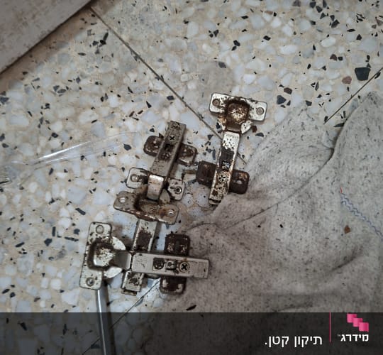 צירי דלת ישנים וחלודים שהוסרו במהלך עבודת החלפת צירים